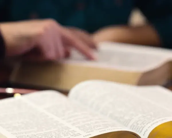 Hände studieren die Bibel, ein Symbol für tiefen Glauben und spirituelle Suche.