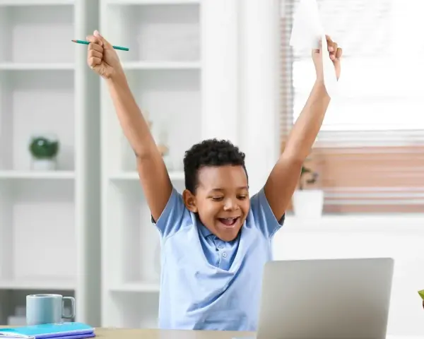 Niño celebra con un lápiz y papel, ¡cosas que dan suerte para un examen!