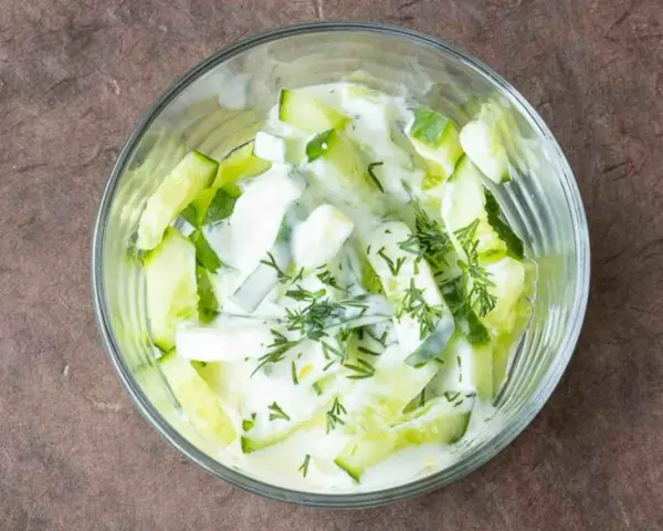 Erfrischender Gurken Dill Salat in einer Glasschüssel, cremiges Dressing mit frischen Kräutern.