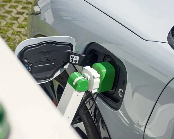 Zielony kabel ładowarki podłączony do portu ładowania samochodu elektrycznego.