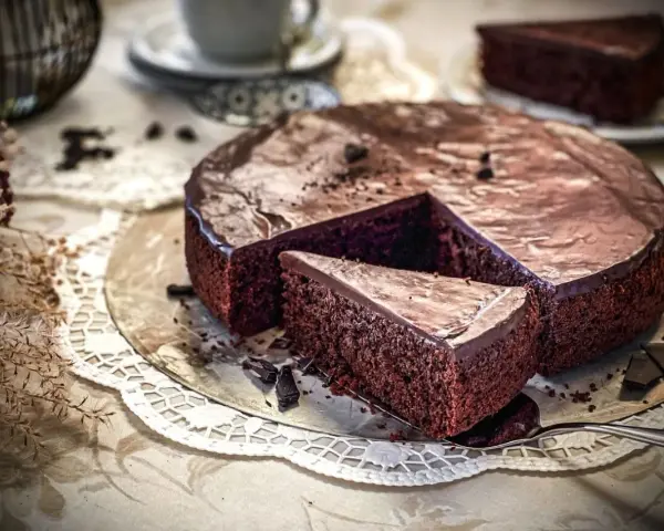 Ein saftiger Schokokuchen mit glänzender Glasur, ein Stück herausgeschnitten. Perfekt für ein Schokokuchen Rezept.