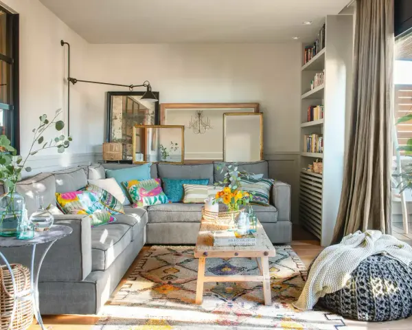 Salones muy pequeños con encanto: sofá gris, cojines coloridos, alfombra étnica, mesa de madera rústica y plantas.