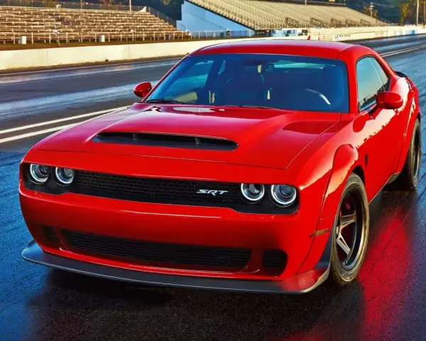 Czerwony Dodge Challenger SRT na torze wyścigowym. Potężny silnik 5.7 Hemi, choć jego spalanie może być wysokie, zapewnia niezapomniane wrażenia.