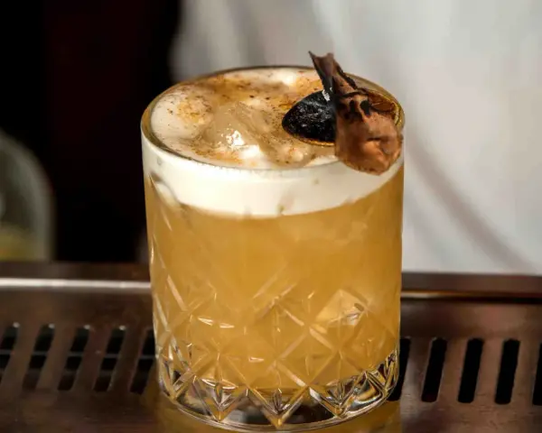 Elegancki Whisky Sour i Amaretto Sour z pianką i dekoracją na barze.