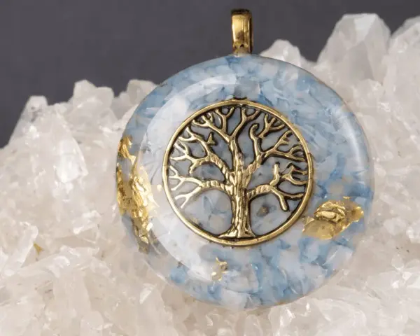 Colgante de orgonita con árbol de la vida dorado sobre fondo de cuarzo. El significado de la orgonita se refleja en su energía protectora.