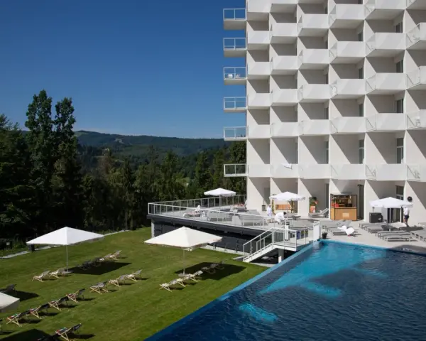 Nowoczesny hotel Crystal Mountain Resort z basenem i leżakami na trawie, otoczony zielonymi wzgórzami.