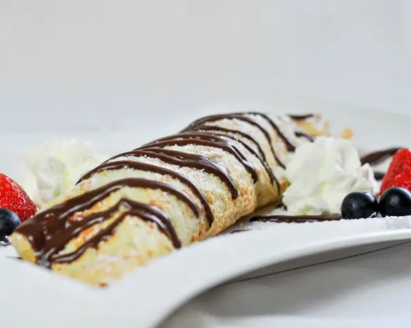 Palatschinken mit Eis, Schokosauce und frischen Beeren. Ein süßer Genuss, der auf der Zunge zergeht.