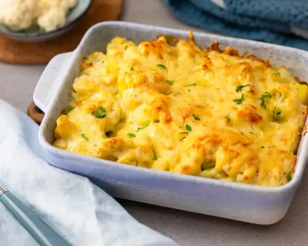 Herzhafter blumenkohl kartoffel auflauf mit geschmolzenem Käse und Petersilie garniert, bereit zum Servieren.
