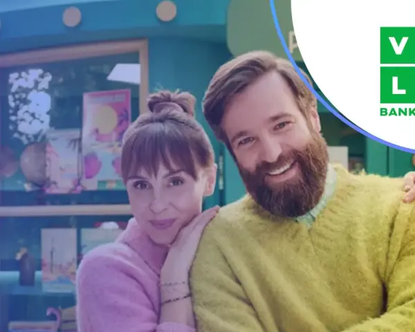 Uśmiechnięta para przed budką z logo Velo Bank. Dowiedz się, velo bank co to za bank i jakie ma oferty.