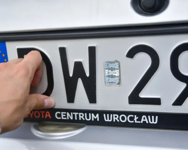 Dłoń zasłania literę "D" na tablicy rejestracyjnej DW 29. Widoczny hologram i napis "TOYOTA CENTRUM WROCŁAW".