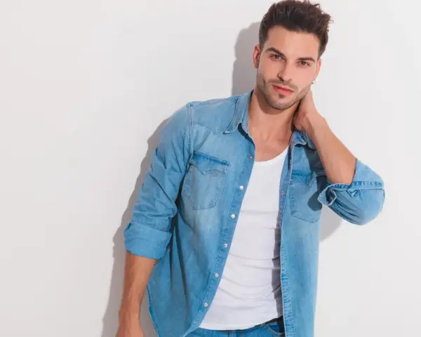 Uomo con un outfit camicia jeans, maglietta bianca e jeans.