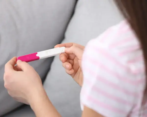 Dłonie trzymające test ciążowy. Wynik wskazuje na 1 miesiąc ciąży, co może być początkiem nowej, pięknej historii.
