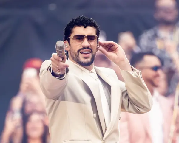 Bad Bunny w beżowym garniturze, z mikrofonem w dłoni, czuje energię tłumu.