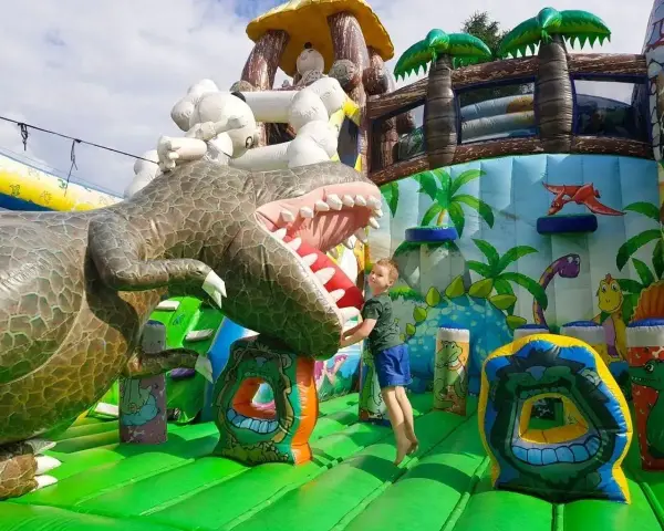 Chłopiec skacze na dmuchanym dinozaurze. Wspaniała atrakcja dla dzieci, jedno z wielu **ciekawe miejsca do 100 km od Katowic**.