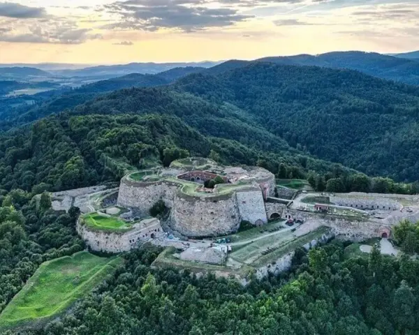Twierdza na wzgórzu, niczym srebrna góra, otoczona zielonymi lasami.