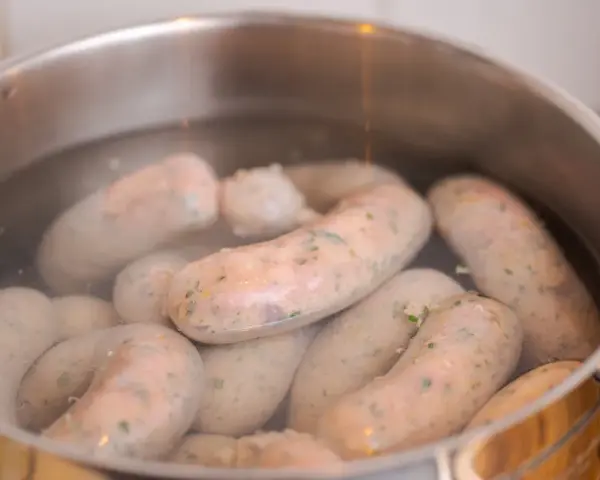 Biała kiełbasa gotuje się w garnku. Poznaj prosty sposób, jak parzyć białą kiełbasę, by była idealna.
