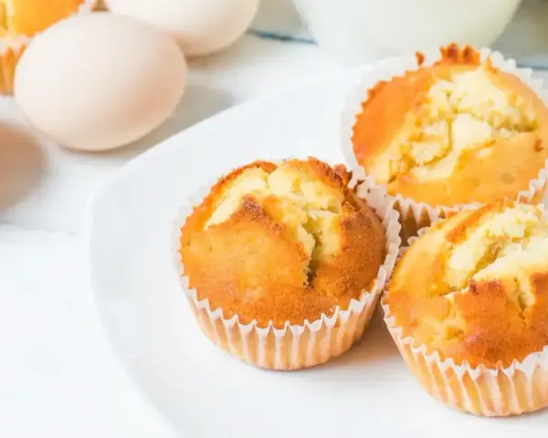 Puszyste babeczki z airfryer na białym talerzu, obok jajka. Idealne na szybkie śniadanie.