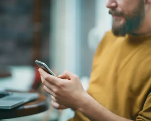 Uomo con barba usa smartphone, forse per capire cosa sono i gb del cellulare e quanto spazio ha per foto e app.