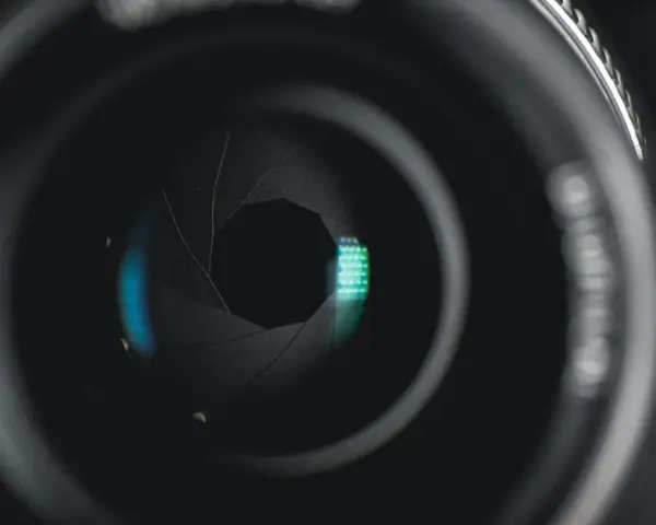 Ouverture d'objectif de caméra, diaphragme réglé sur f 2.8, révélant des reflets bleus et verts.