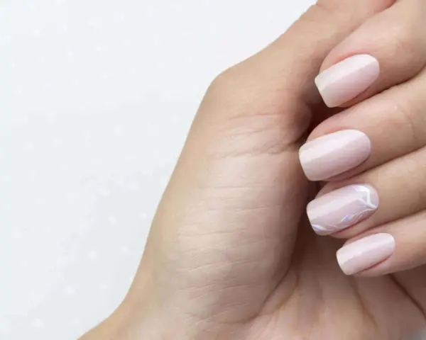 Main gauche avec des ongles pastel, dont un orné d'un motif floral délicat. Parfait pour faire les ongles.