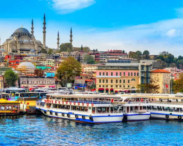 A vibrant cityscape of Istanbul, with the Suleymaniye Mosque dominating the skyline. Ferries and buses line the waterfront, ready for a 3-day Istanbul adventure.