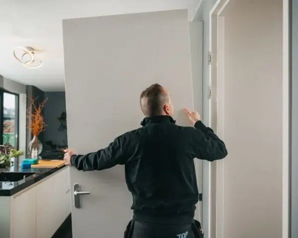 Pracownik montuje drzwi, tworząc wykucie otworu na drzwi w nowoczesnym wnętrzu.
