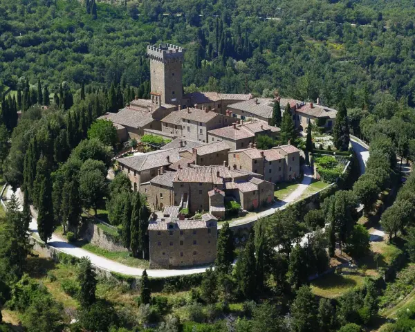 Il castello di Gargonza, un borgo medievale in pietra con torre, immerso nel verde della Toscana.