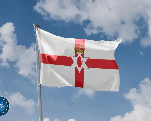 Flaga Irlandii Północnej powiewa na tle błękitnego nieba z chmurami. Symbolizuje historię i tożsamość regionu.