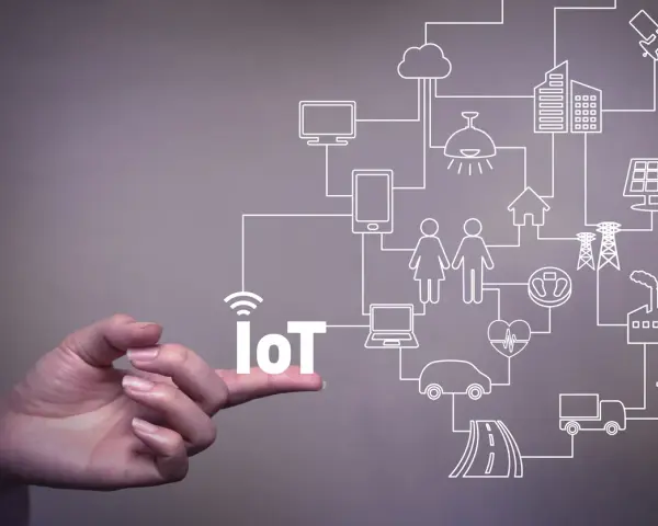 A hand points to the word "IoT," illustrating the vast network of connected devices and systems that offer significant **iot benefits for business**, from smart homes to factories.