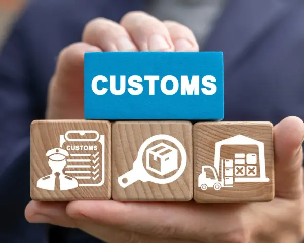 Klocki z symbolami celnymi i napisem "CUSTOMS" ilustrują proces odprawy towarów importowanych.