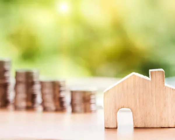 Une petite maison en bois et des piles de pièces de monnaie suggèrent un coup de pouce pour quel groupe : les investisseurs immobiliers.