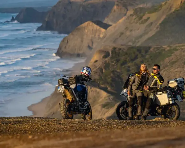 Para motocyklistów odpoczywa na klifie, podziwiając dzikie wybrzeże Algarve. Ich motocykle gotowe do dalszej podróży.