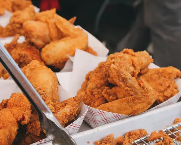 Un surtido de crujiente pollo frito en recipientes de cartón. Las piezas doradas y sabrosas invitan a disfrutar de este clásico.