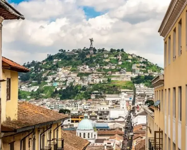 Widok na wzgórze z pomnikiem w Quito, stolicy Ekwadoru. Kolorowe budynki i wąskie uliczki tworzą malowniczy krajobraz.