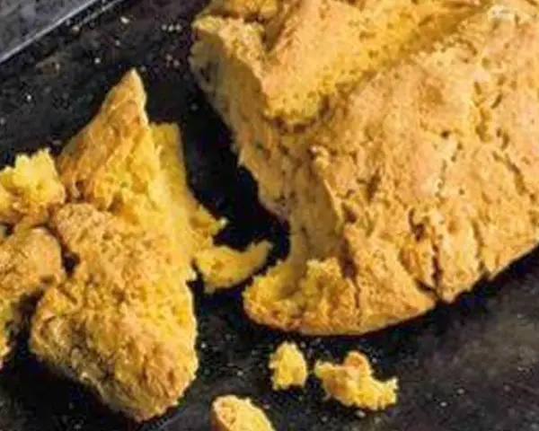 Goldgelbes, rustikales Brot, das nach Rezepten mit Lupinen aussieht, liegt auf einem dunklen Blech.