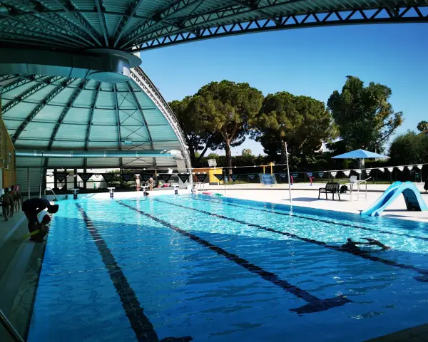 Piscine intérieure avec toboggan bleu, lignes de nage et quelques personnes.