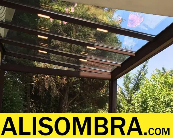 Techo de cristal para montera patio interior, con luces integradas y vistas a árboles frondosos.