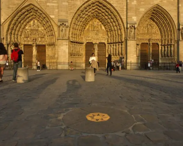 Devant Notre-Dame, le point zéro altitude marque le centre de Paris. Des visiteurs admirent la façade.