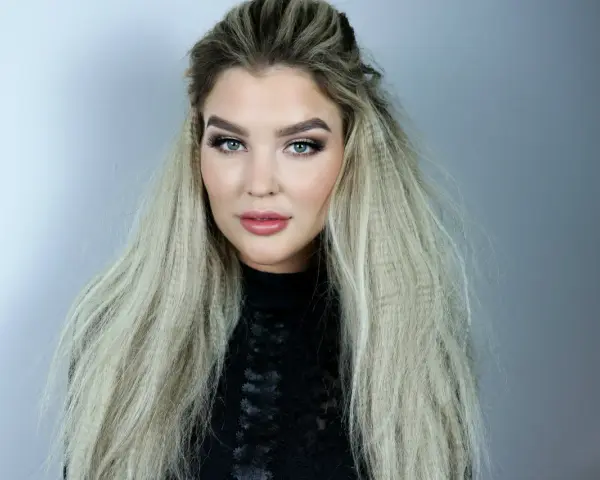 En kvinna med blå ögon och en snygg makeup har sitt blonda hår stylat med en våffla.