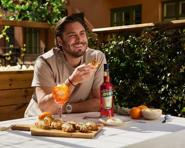 Man njuter av en Aperol Spritz och tilltugg på en solig uteservering.