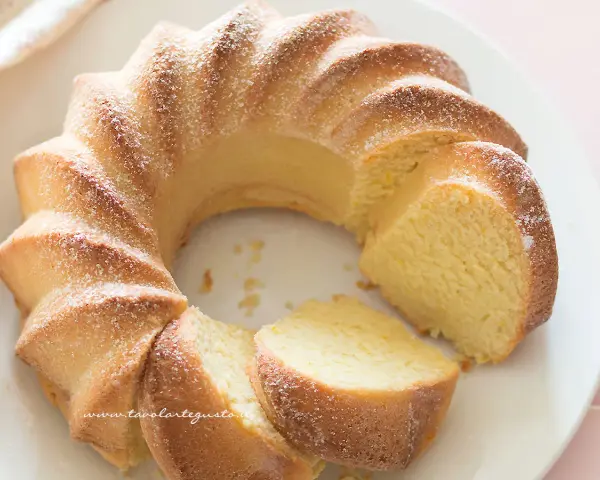 Una soffice torta di ricotta, spolverata di zucchero a velo, con una fetta tagliata.