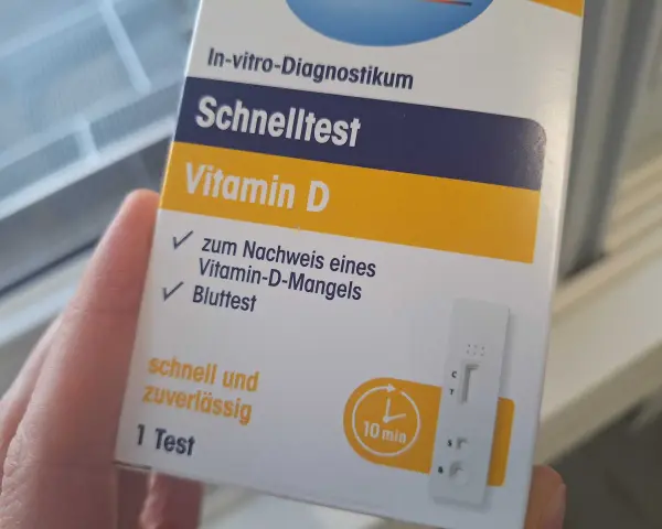 Hand hält eine Verpackung für einen Vitamin-D-Schnelltest mit einem Bluttest-Streifen.