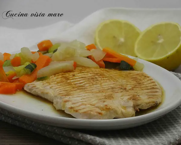 Fettine di tacchino appetitose, cotte alla griglia, servite con verdure miste e spicchi di limone.