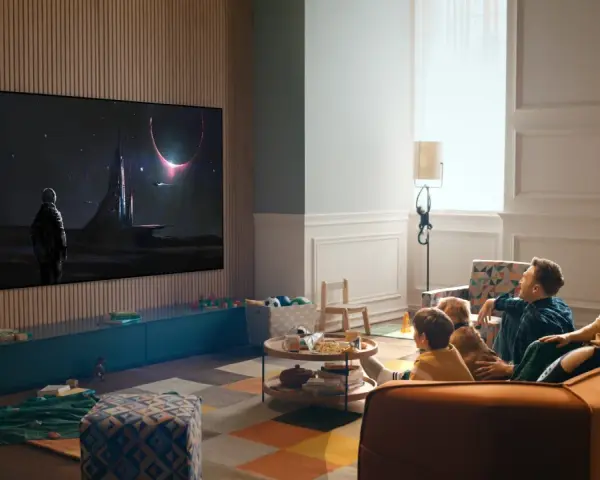 Familj tittar på en rymdfilm på TV:n, kanske via iptv tele2. En astronaut står framför en futuristisk stad under en solförmörkelse.