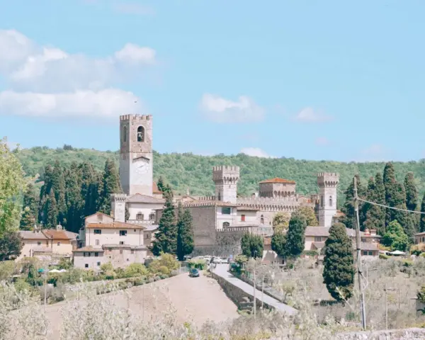 La Badia a Passignano, un borgo medievale toscano con un'imponente torre dell'orologio, circondato da colline verdi e cipressi.