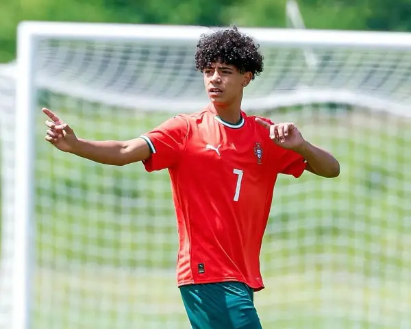 Cristiano Ronaldo Jr. con pelo rizado y camiseta roja con el número 7, señalando con el dedo índice.