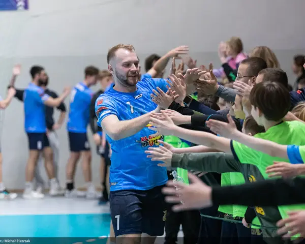 Gracz MKS Wieluń w niebieskiej koszulce z numerem 1 daje "piątki" młodym kibicom.