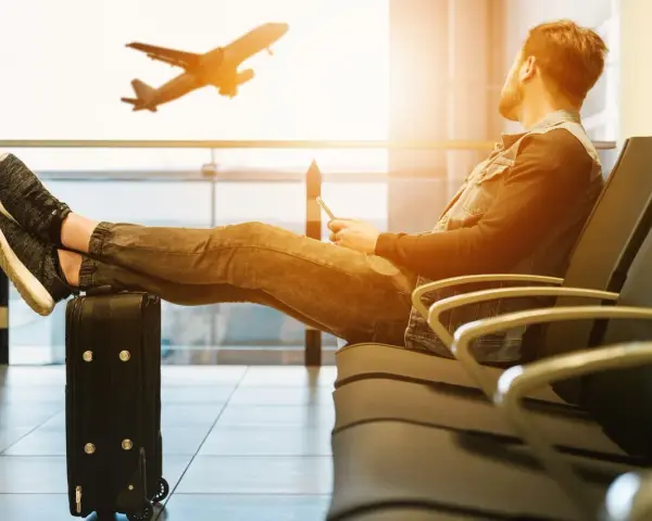 Mężczyzna czeka na lotnisku, nogi na walizce, samolot Wizzair startuje. Czyżby overbooking?