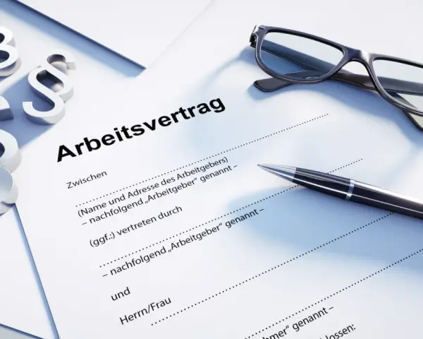 Drei Paragraphen-Symbole, eine Brille und ein Stift liegen auf einem Dokument mit der Überschrift "Arbeitsvertrag". Dies unterstreicht, dass ein Arbeitsvertrag schriftlich sein muss.