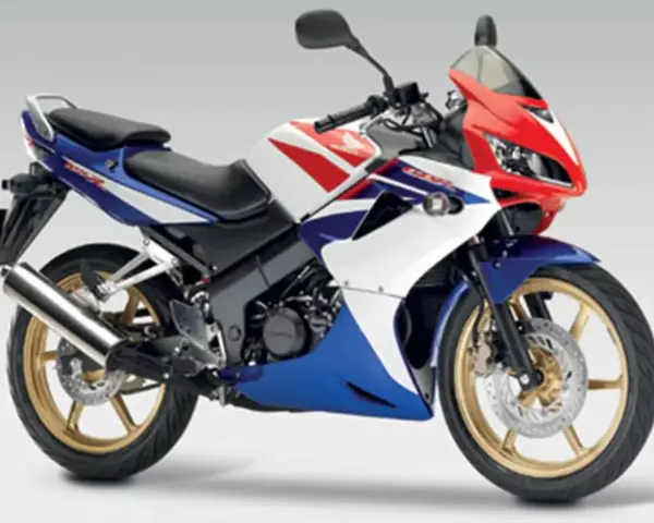 Sportowy motocykl Honda CBR 125R w barwach V-Max, z czerwonym, białym i niebieskim malowaniem.